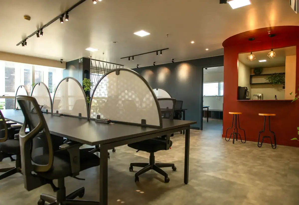 Estações de trabalho com divisórias em arco e copa em nicho vermelho com banquetas