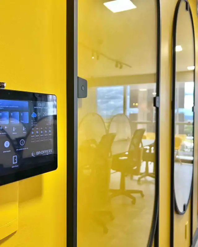 Painel de automação na parede amarela de um escritório personalizado, ao lado de salas com portas de vidro em arco