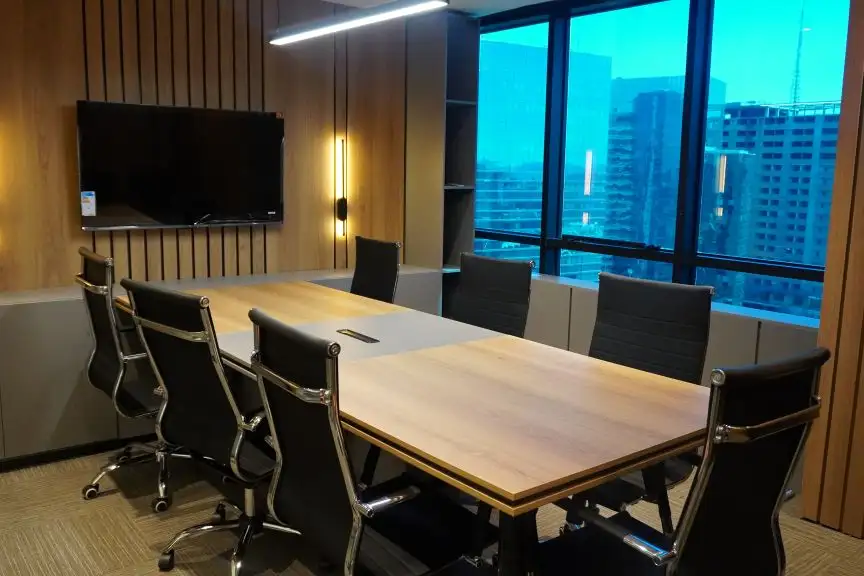 Sala de reunião do Number One com mesa clara, cadeiras pretas, tela e janelas para a cidade