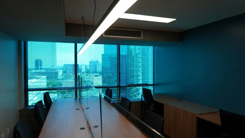 Estações de trabalho com divisórias de vidro junto à janela, com vista para a cidade