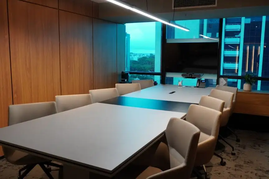 Sala de reunião da unidade Number One com mesa clara, cadeiras e iluminação azul