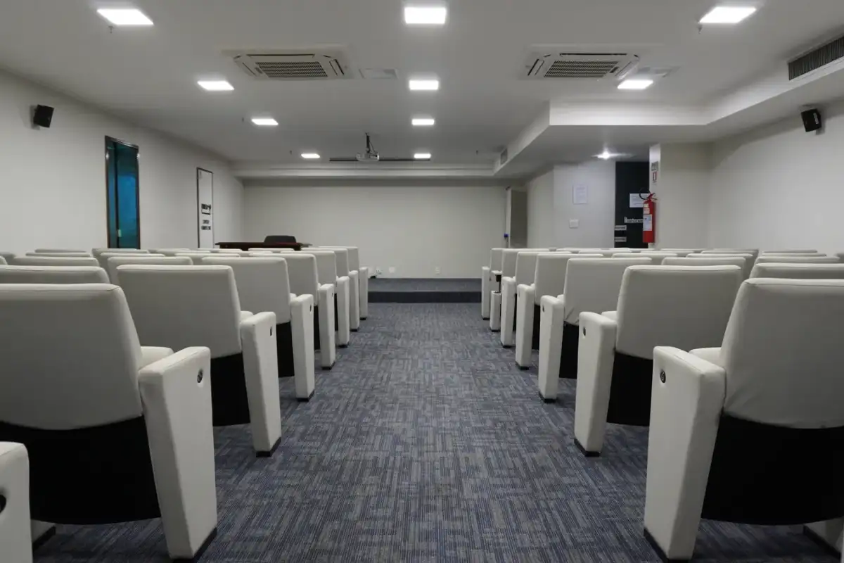 Auditório da unidade Number One da BROffices, com poltronas brancas e corredor central