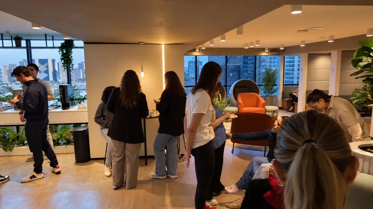 Participantes do Cake reunidos no lounge da BROffices, com vista de Brasília ao fim da tarde