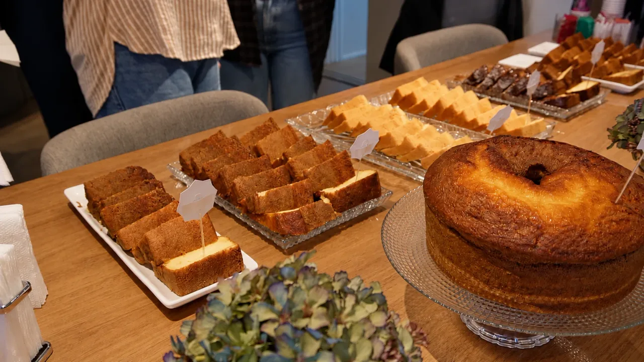 Mesa do Cake BROffices com bolo caseiro, fatias de bolo e doces em bandejas de vidro