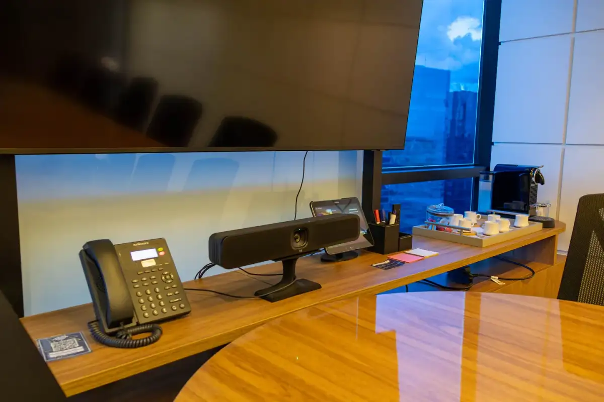 Detalhe da barra de videoconferência com câmera, sistema de áudio e painel de controle abaixo da tela da sala Flamboyant, no Number One