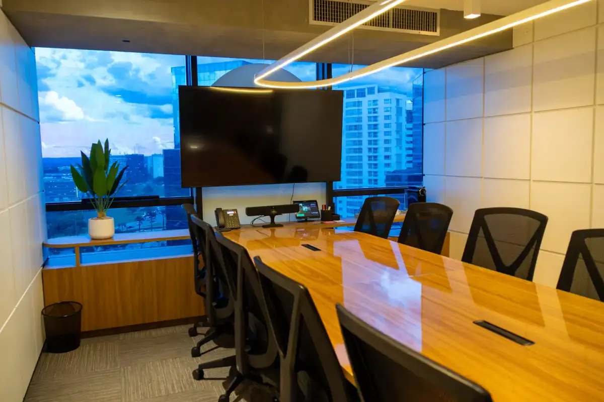 Sala de reunião Flamboyant do Number One com mesa de madeira, cadeiras executivas, tela e vista da cidade