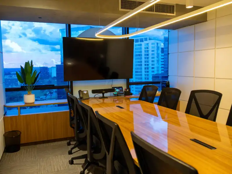 Sala de reunião da unidade Number One com mesa de madeira, luminária oval e janela azul para a cidade