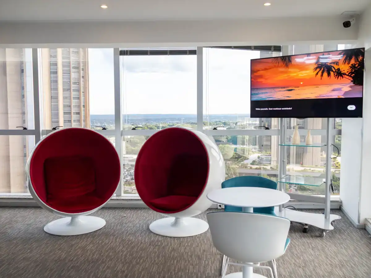 Lounge da unidade Prime Business com poltronas vermelhas em formato de ovo e janelas para a cidade