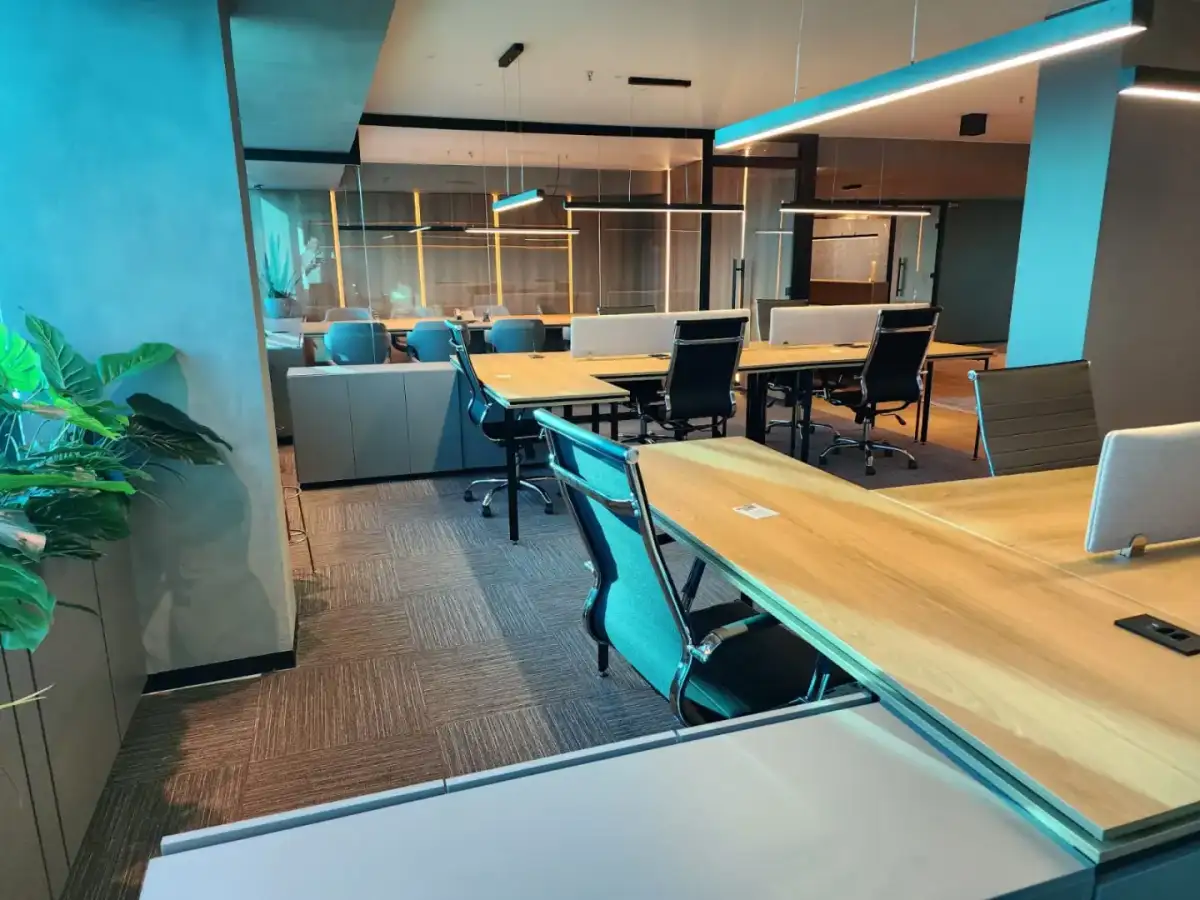 Escritório personalizado em planta aberta com estações de trabalho em madeira, salas envidraçadas e iluminação linear