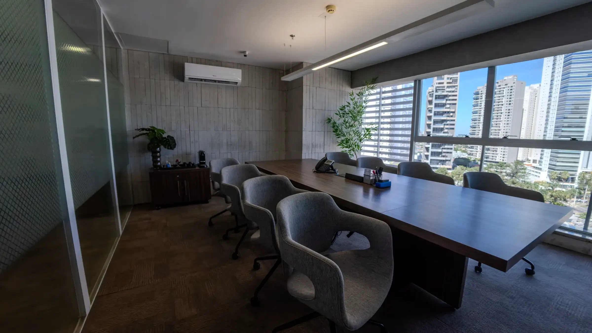 Sala de reunião da unidade Nasa Business Style, em Goiânia, com mesa longa de madeira, cadeiras cinza e janelas para a cidade