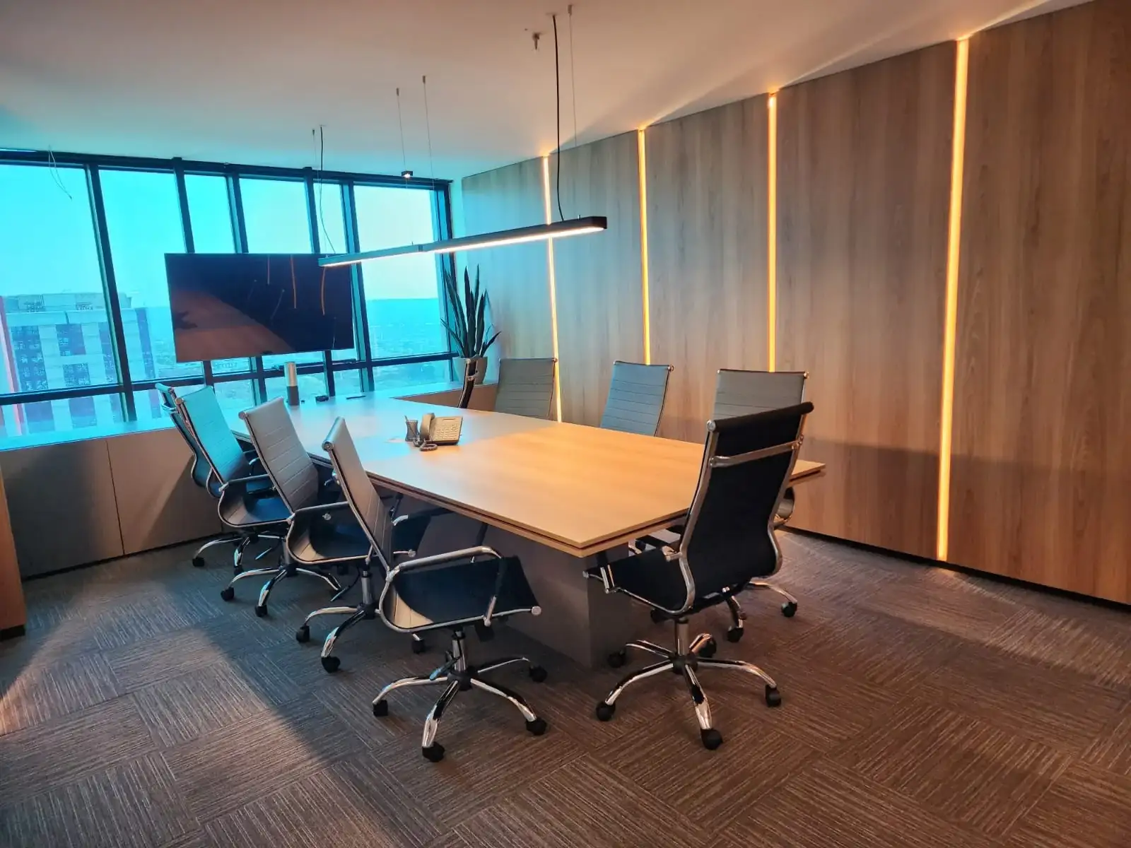Sala de reunião da BROffices com mesa de madeira, tela e iluminação natural
