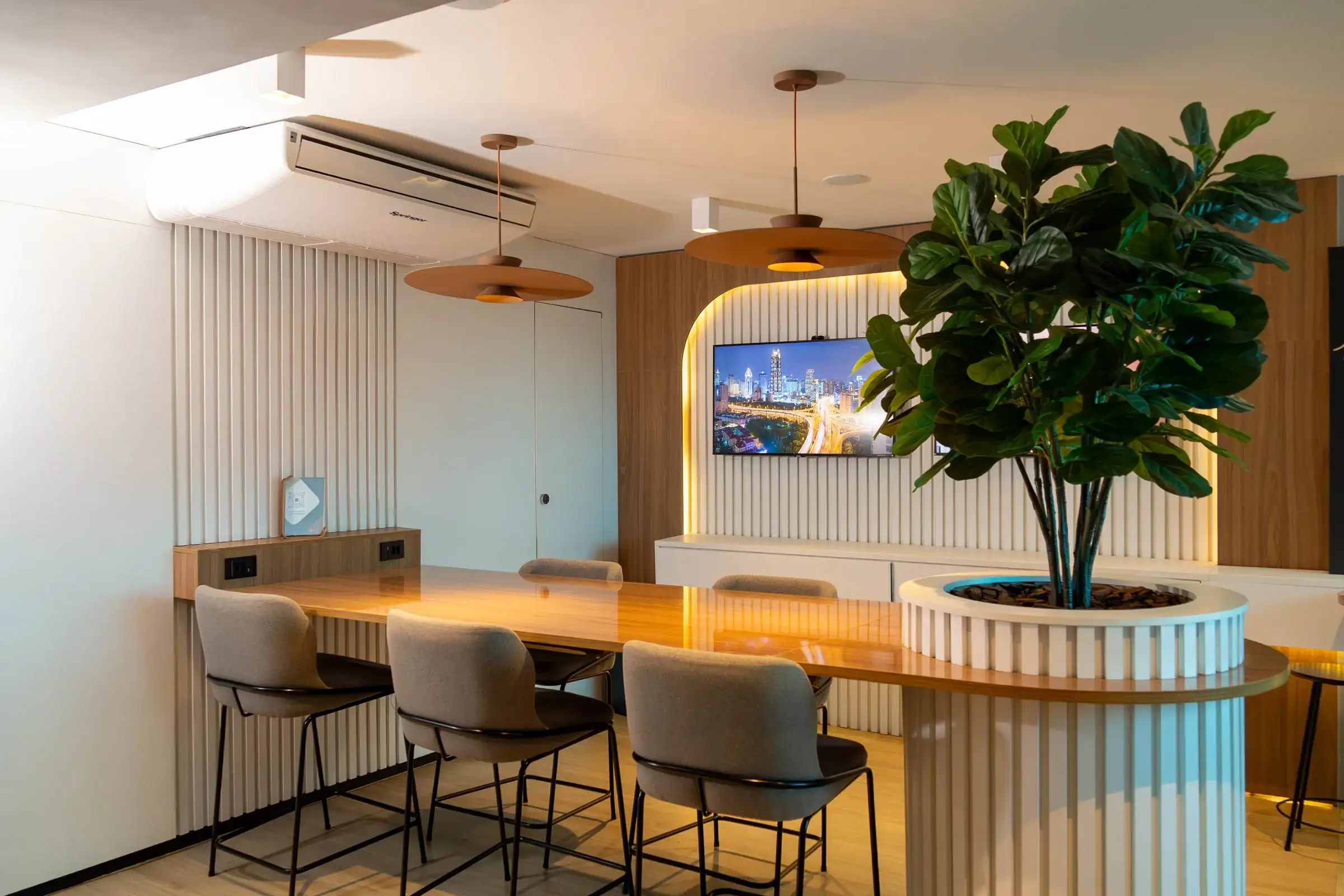 Café do 17º andar da unidade Number One com bancada de madeira em torno de uma árvore, banquetas e iluminação acolhedora